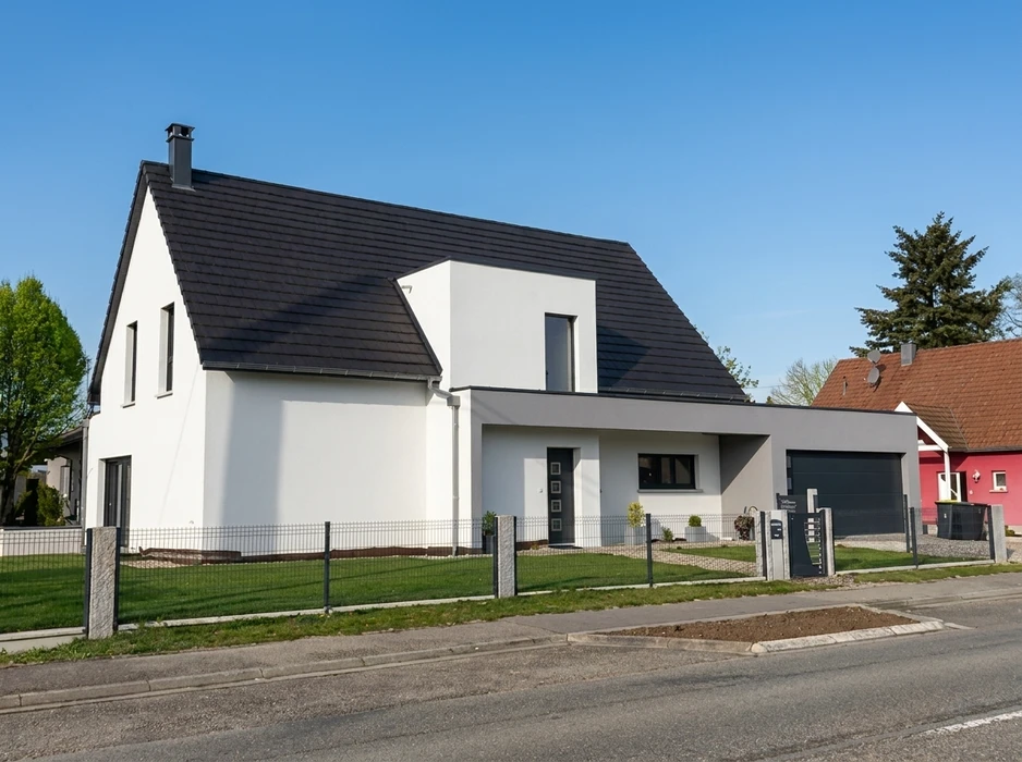 Maison individuelle moderne, façade blanche avec toiture en ardoise anthracite à deux pans, lucarne cubique intégrée