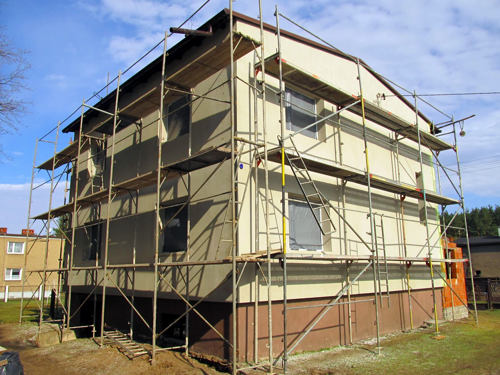 Chantier de construction extérieur avec maison individuelle en cours de rénovation énergétique
