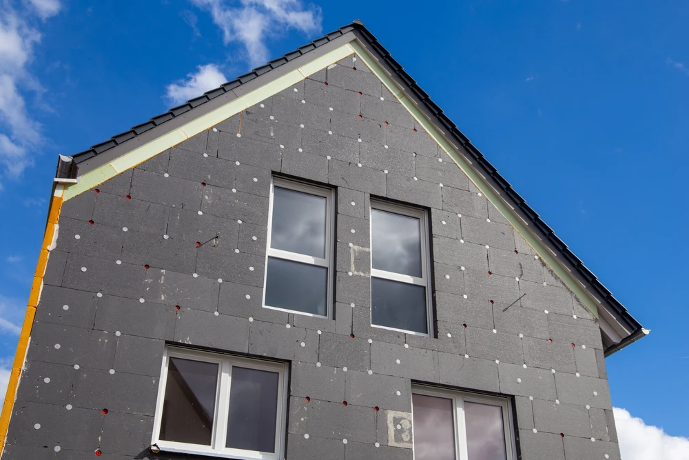 Chantier de construction résidentielle en cours, façade d'une maison neuve avec système d'isolation thermique par l'extérieur (ITE)