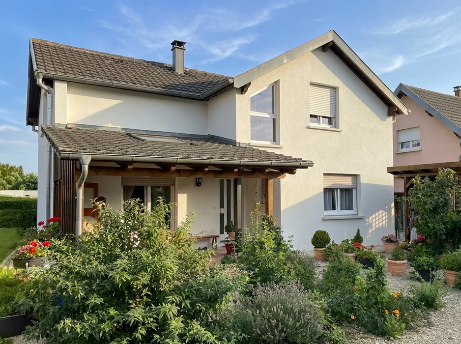 Maison individuelle à deux étages, façade enduit blanc, toiture tuiles brun foncé, avec pergola bois en façade avant