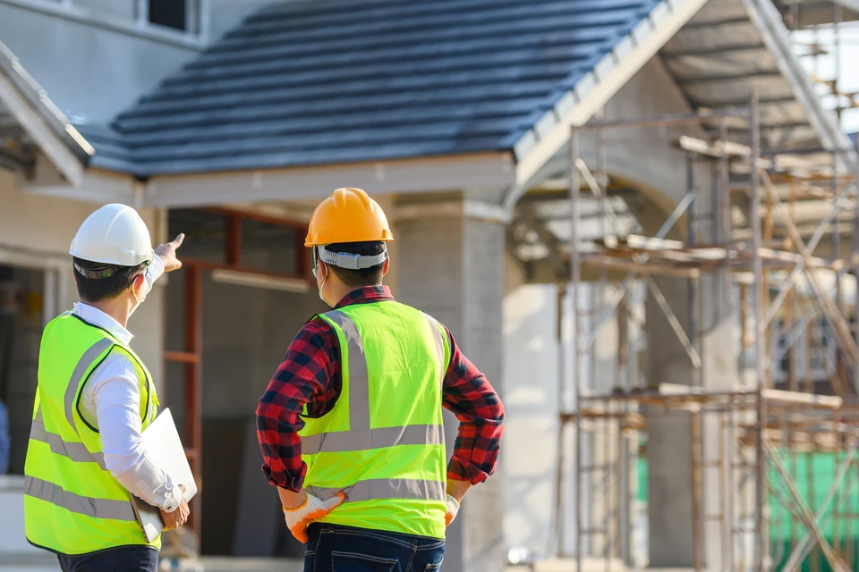 Chantier extérieur avec trois ouvriers équipés de harnais de sécurité rouge travaillant sur échafaudage métallique
